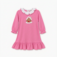 A pink long-sleeve baby dress with a ruffled white collar, elastic cuffs, and a ruffled hem, featuring an embroidered gingerbread house motif on the chest.
