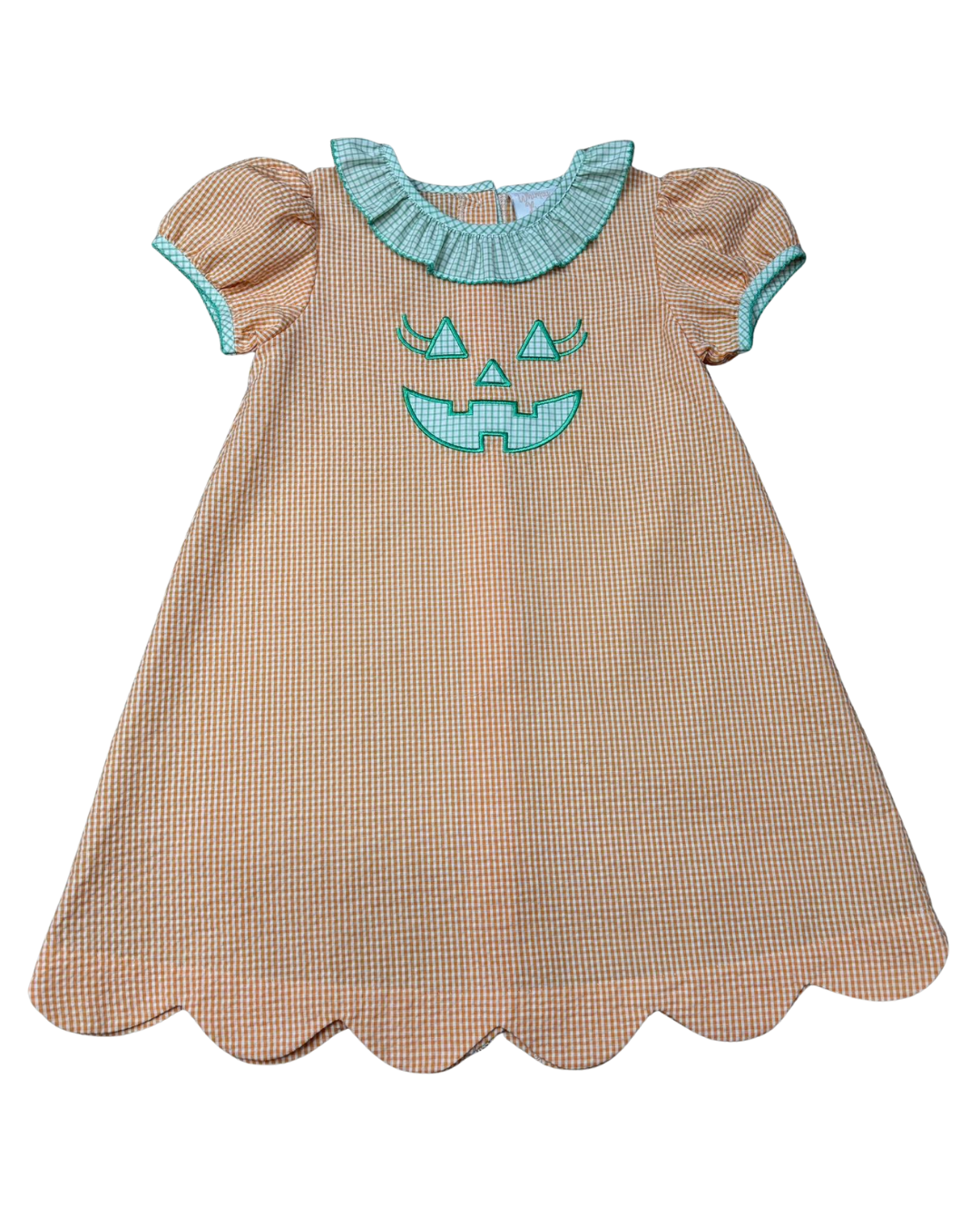 A toddler girl's dress featuring a beige and white gingham pattern, a scalloped hem, short puff sleeves with light blue trim, and a light blue ruffled collar. The front is decorated with a light blue embroidered jack-o'-lantern face.