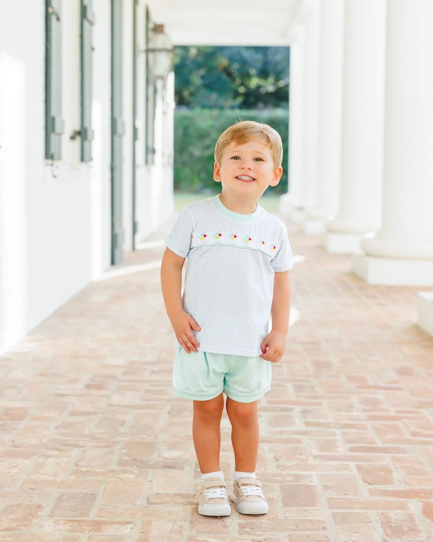 A baby girl's two-piece outfit consisting of a short-sleeve top and matching shorts. The top is white with a very fine light purple grid pattern, featuring a decorative horizontal band across the chest with small colorful embroidered flowers.