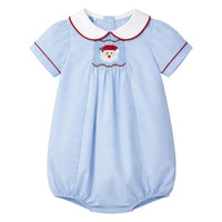 A baby's short-sleeve smocked bubble in light blue, featuring a white Peter Pan collar with red trim, red piping on the sleeves, and Santa Claus embroidery on the chest.