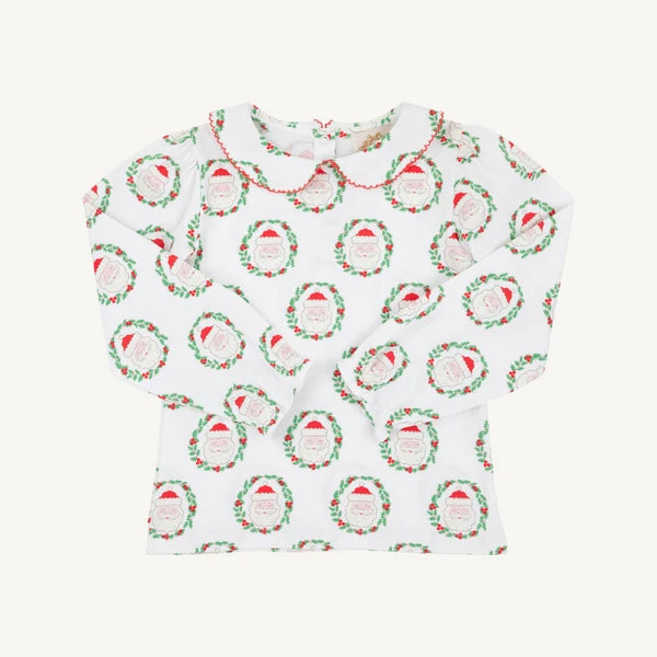 A white long-sleeve baby top with a Peter Pan collar, featuring an all-over print of green wreaths with red berries and Santa hats. The collar is finished with a red stitched trim.